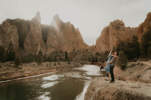 Couple hugging during rocking climbing engagement session at Smith Rock