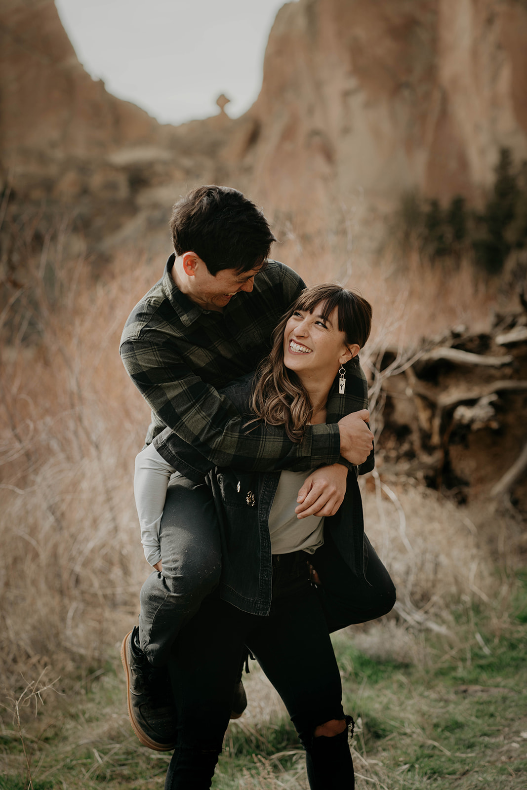 Woman carrying man on her back during engagement session at Smith Rock