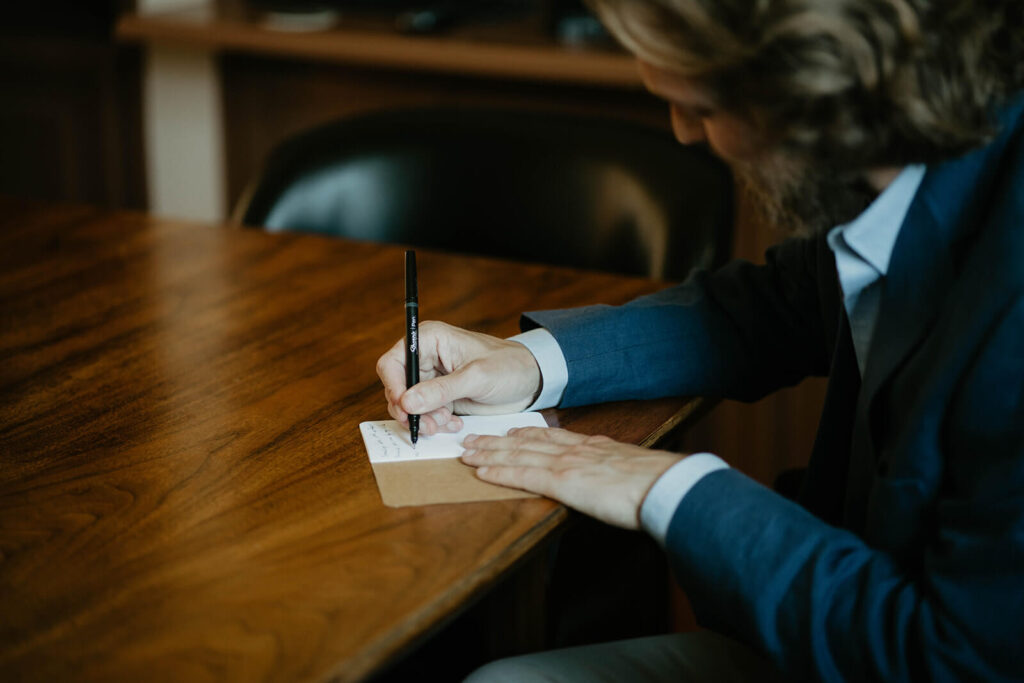 Groom writing vows in vow book for styled wedding shoot