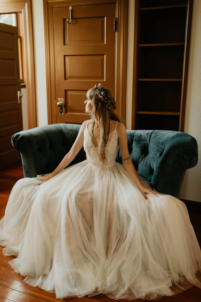 Bride sitting on blue velvet couch in white tulle wedding dress