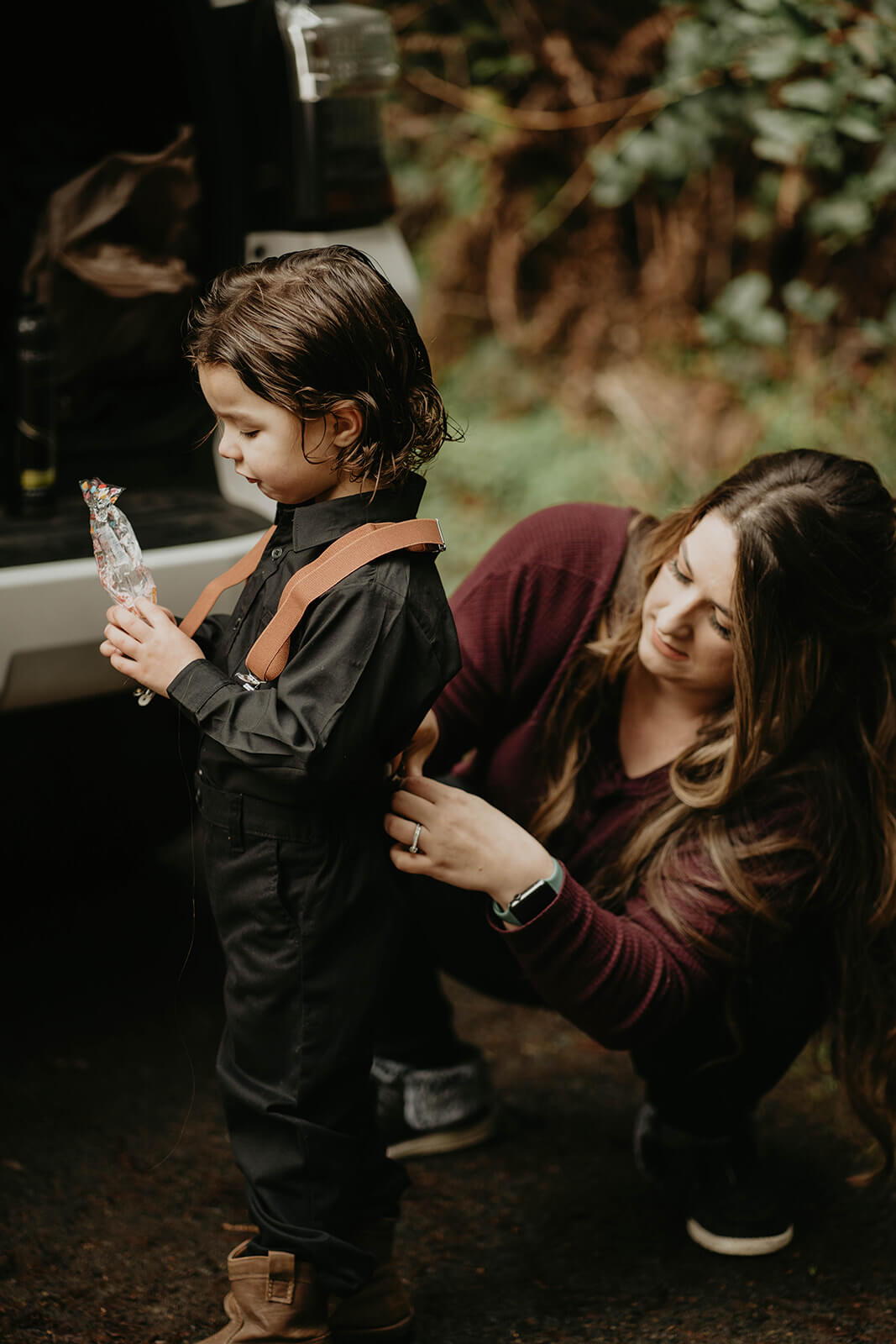 Bride helping little boy get ready for forest elopement