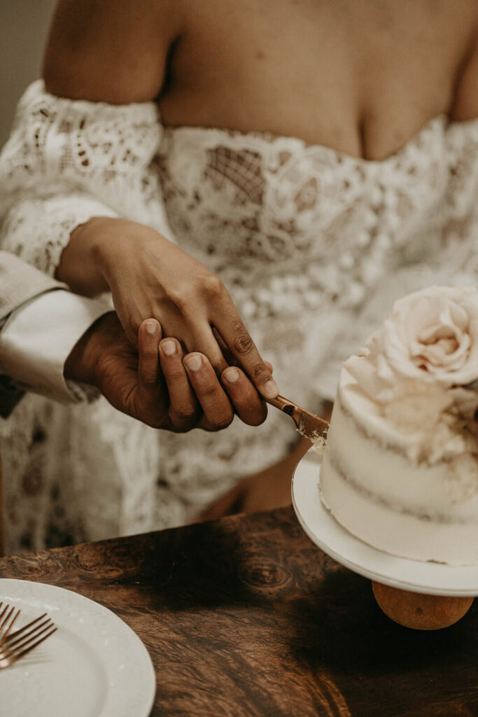 Bride and groom cutting white wedding cake