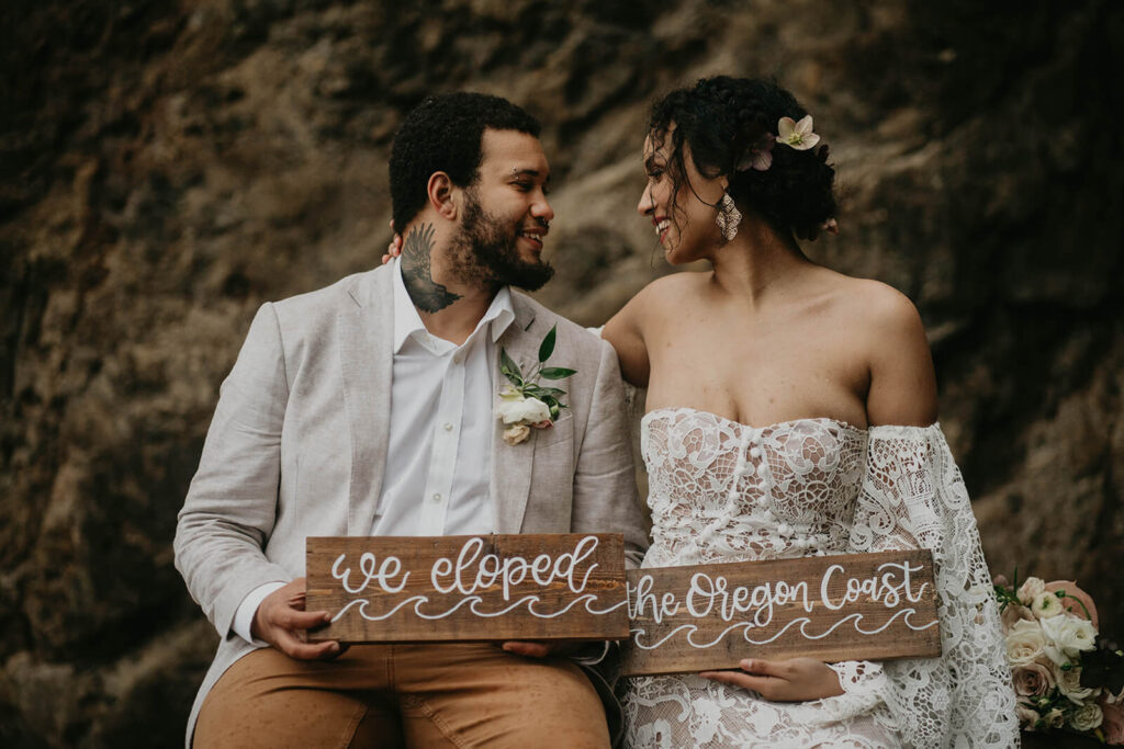 Bride and groom holding "we eloped" signs on the Oregon coast