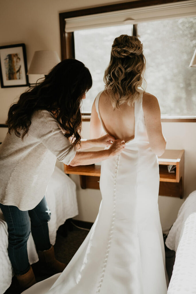 Bride getting into white wedding dress