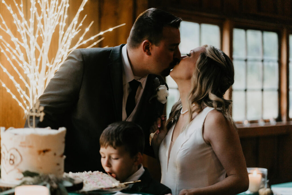 Bride and groom kiss after cutting wedding cake