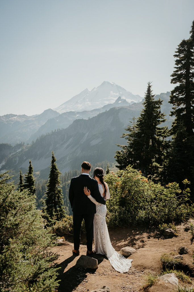 the bride and groom walking in the mountains. 