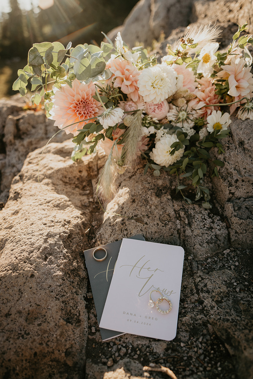 a bouquet of flowers on a rock with the couple's vows and wedding rings. 