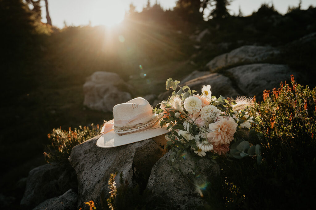 a bouquet of flowers and a cowboy hat on a rock. 