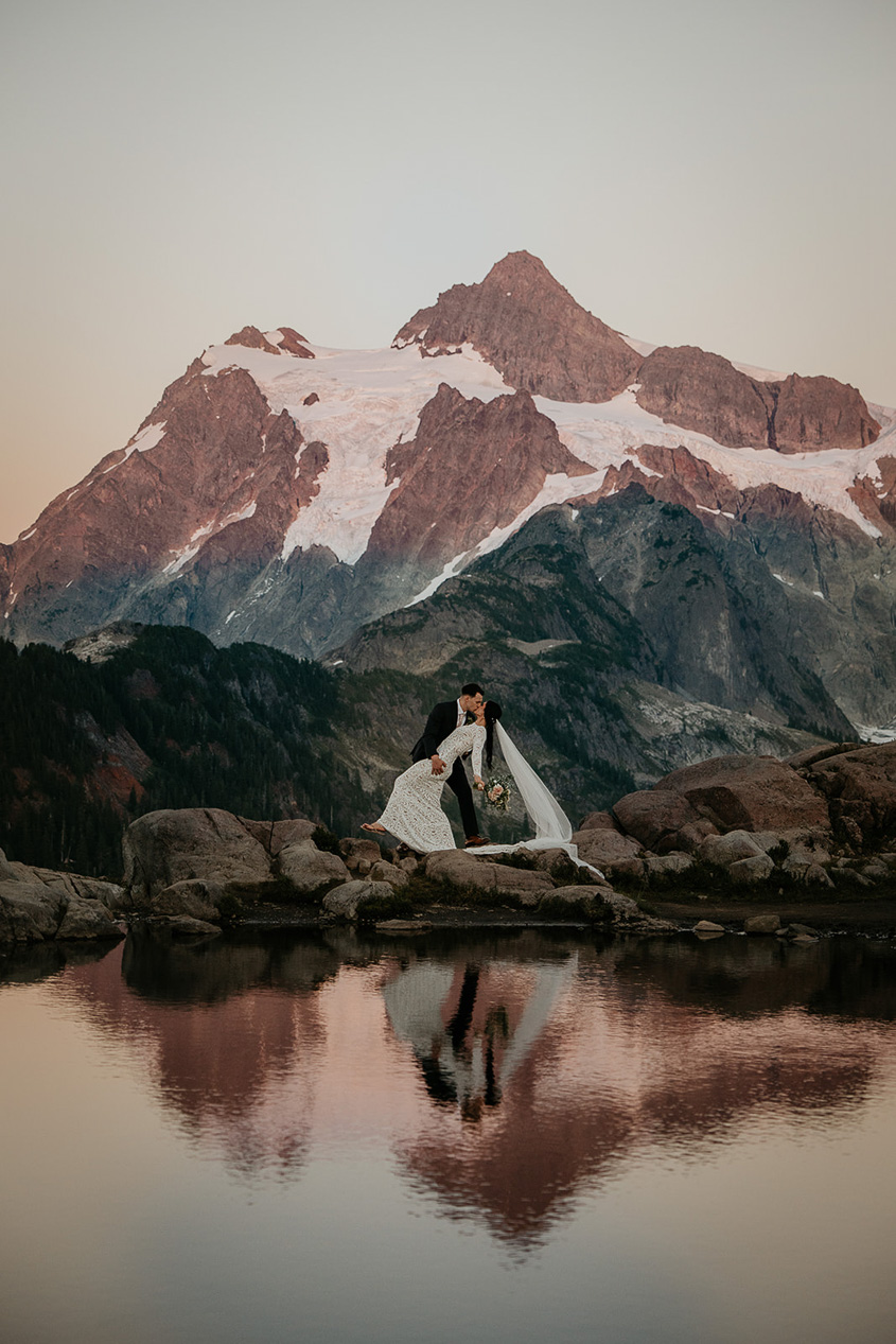 the newlyweds kissing in front of a mountain during their North Cascades elopement.