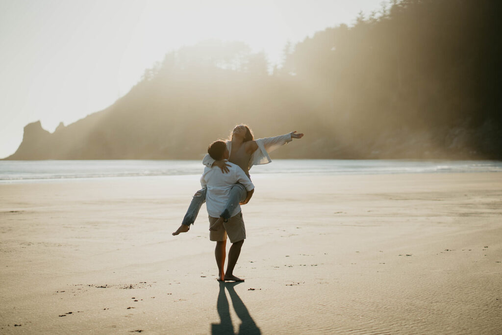 Two women dancing on the beach during Oregon Coast engagement session