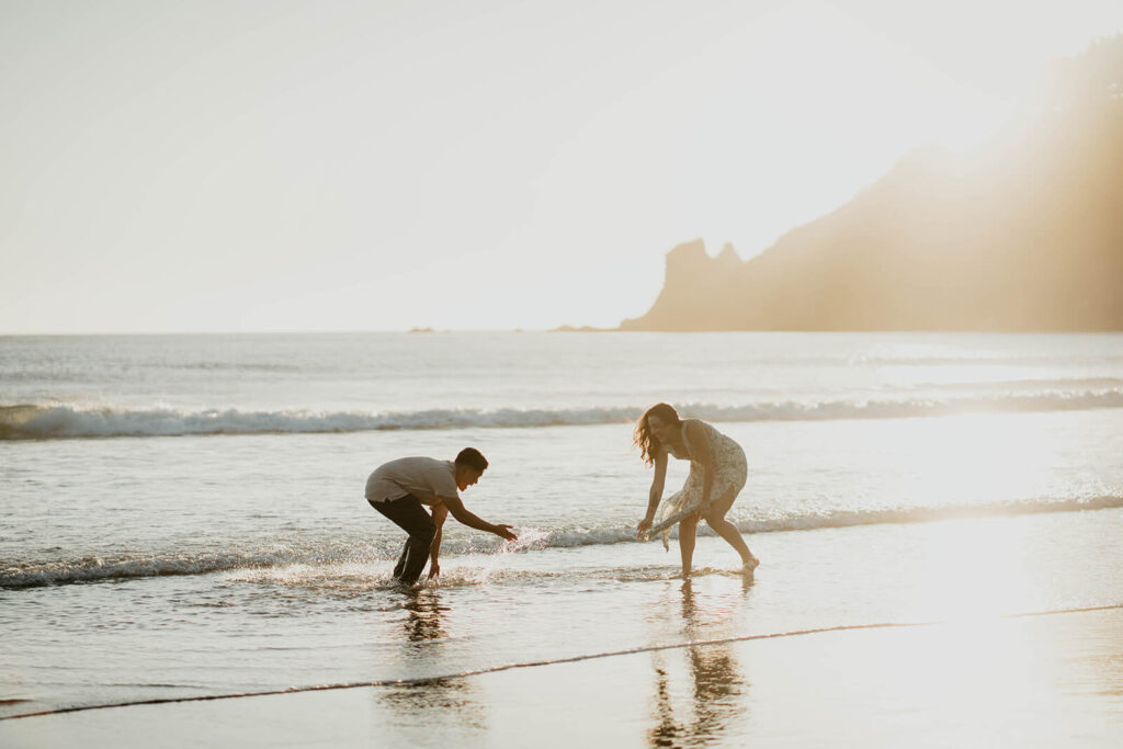 Couple splashing each other in the water on the Oregon Coast