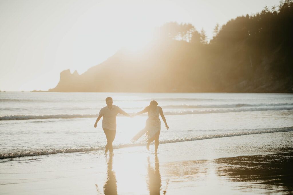 Two women holding hands running on the beach at sunset