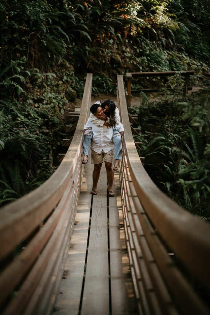 Couple riding piggy back on a suspension bridge 