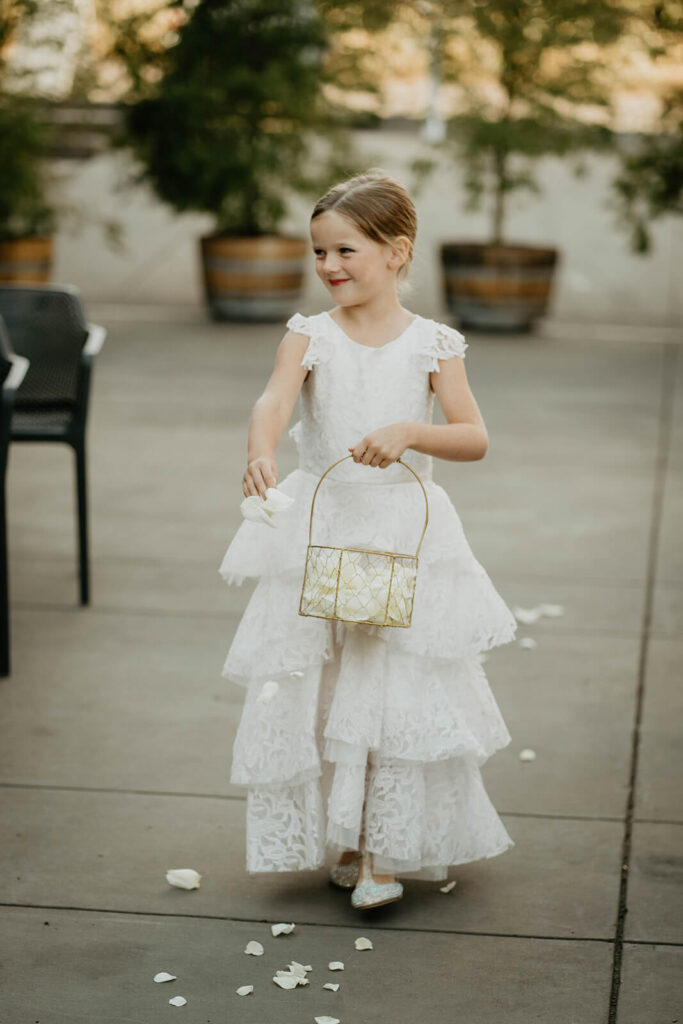 Flower girl dropping petals at Oregon vineyard wedding