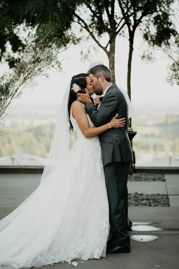 Bride and groom first kiss during vineyard wedding ceremony