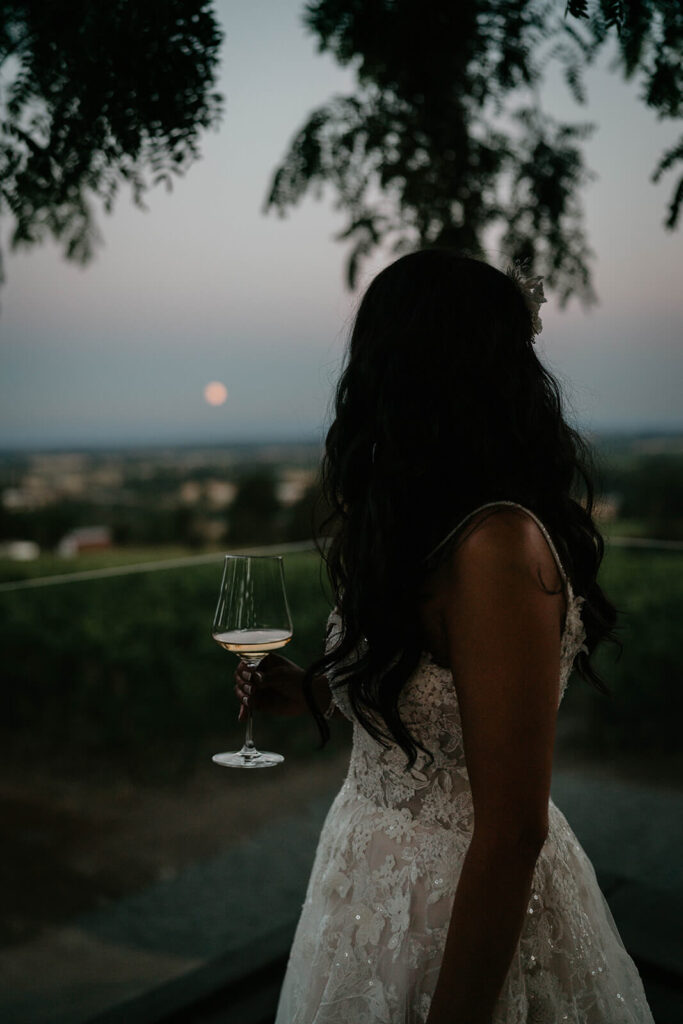 Bride holding wine glass staring out at the moon