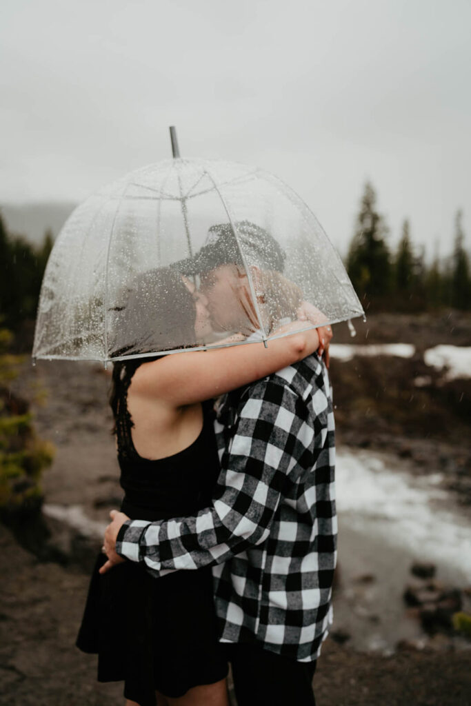 Couple kissing under clear umbrella at Mt Hood