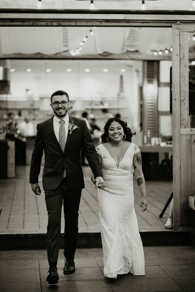 Bride and groom holding hands while entering the dinner reception