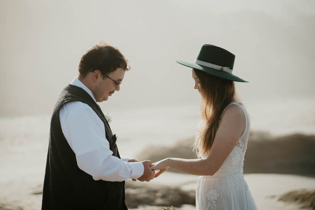 Bride and groom exchange rings during intimate beach wedding ceremony