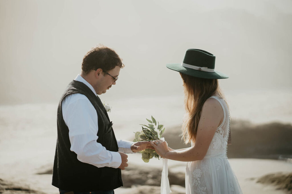 Bride and groom exchange rings during intimate beach wedding ceremony