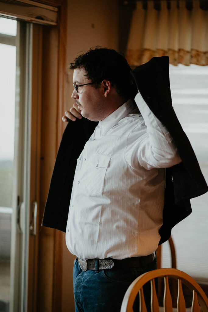 Groom putting on black jacket