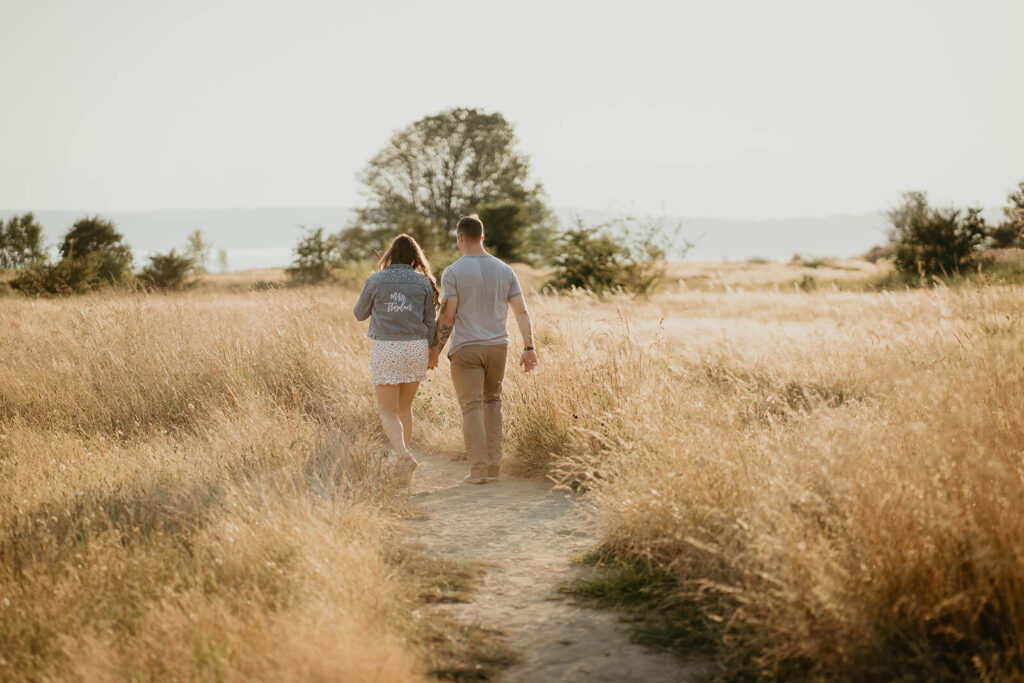 Couple holding hands while walking around Discover Park for their Seattle engagement photos