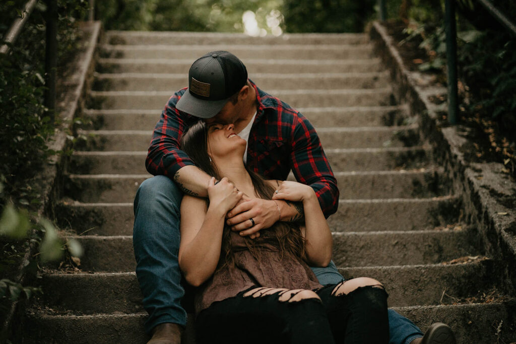 Couple sitting on the steps at Discovery Park during their Seattle engagement photos