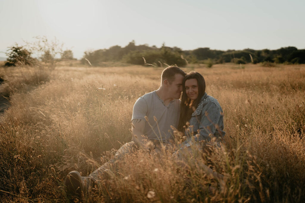 Couple sitting in the grass during their engagement photo session at Discovery Park Seattle