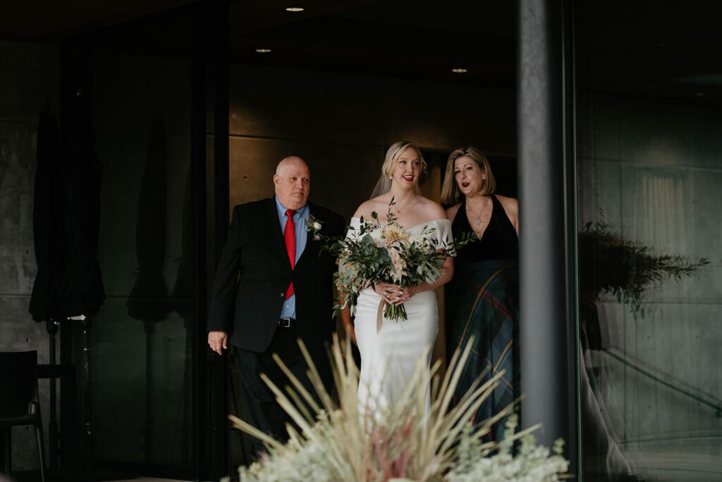 Bride walking with parents down Oregon vineyard wedding aisle 