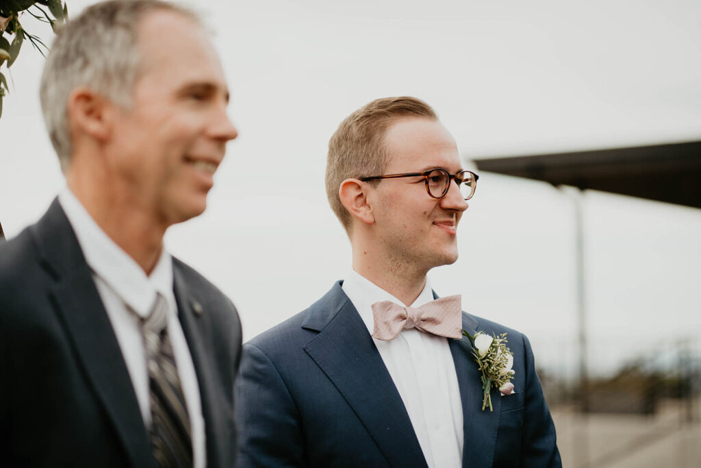 Groom smiling as bride walks down the wedding aisle at Ponzi Vineyards