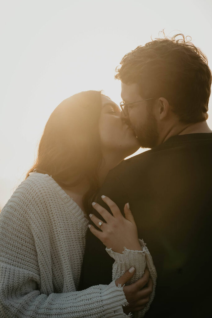 Couple kissing during engagement photos on the beach