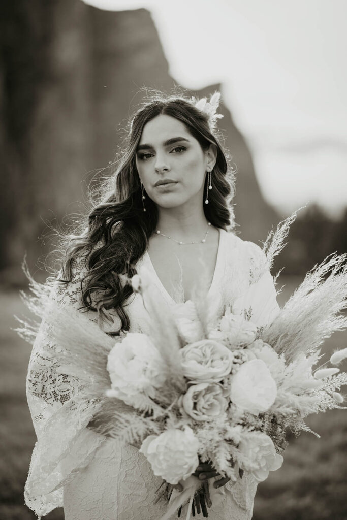 Bride in lace wedding dress holding large neutral floral bouquet