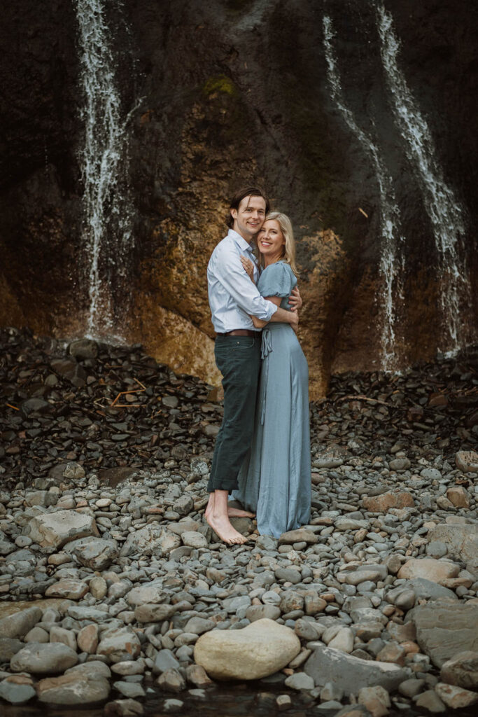 Couple holding hands in front of waterfall at Hug Point State Park