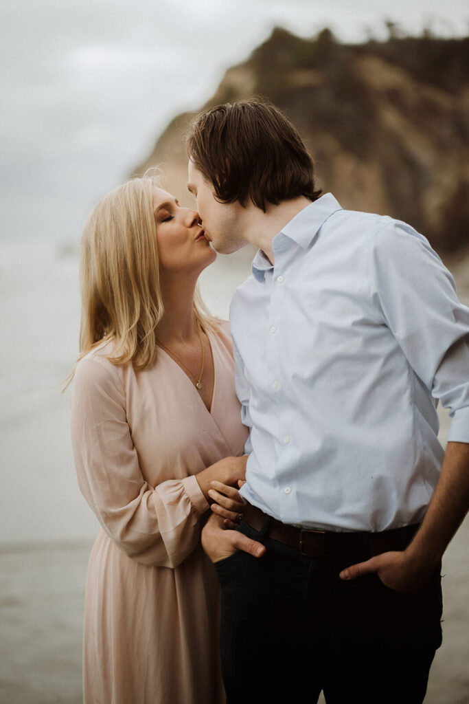 Couple kissing during engagement photo session at Hug Point