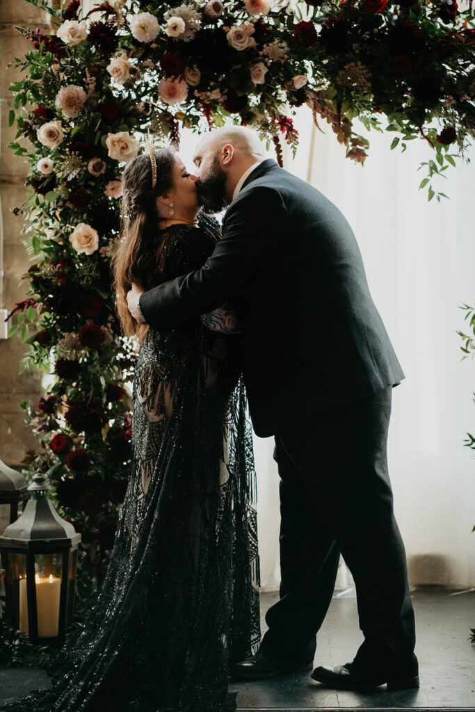 Bride and groom kiss at dark wedding ceremony