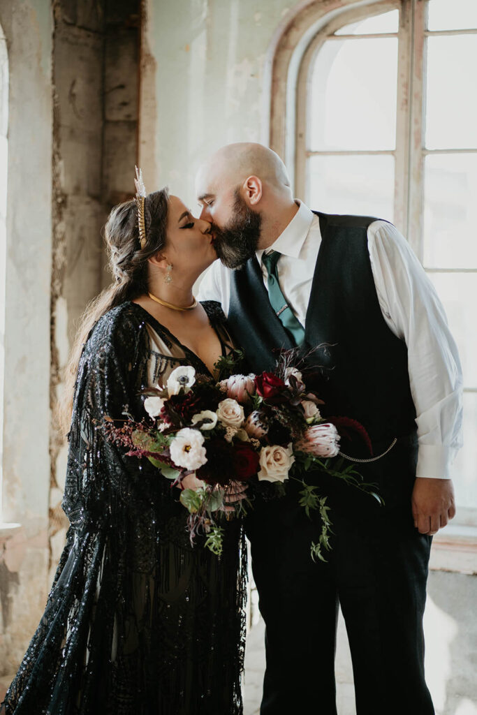 Bride and groom kiss at dark, moody wedding in Oregon