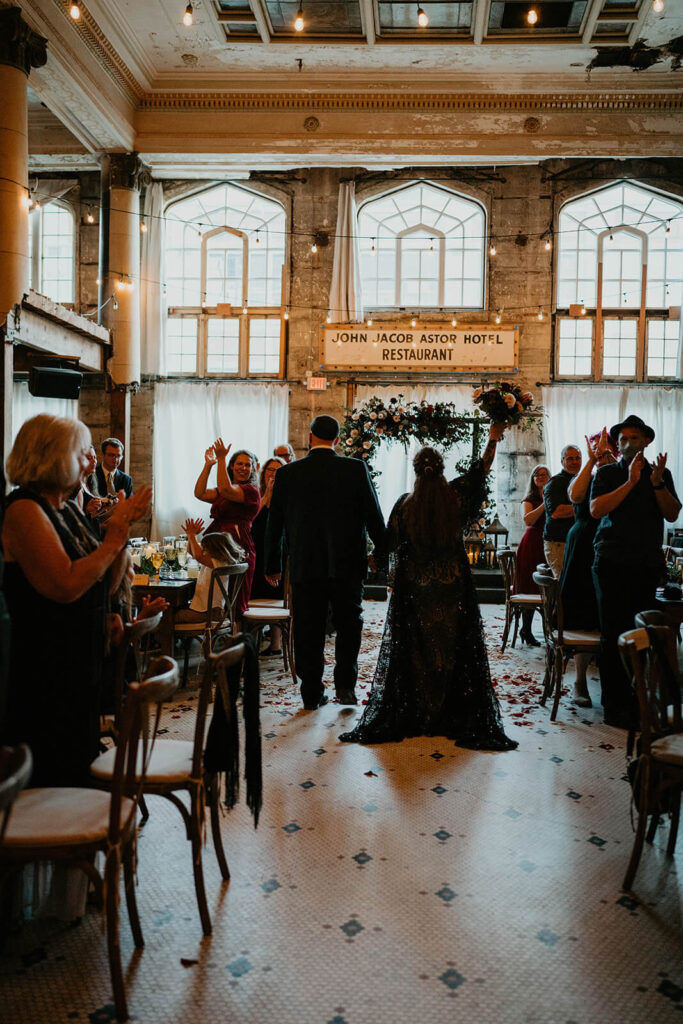 Bride and groom enter dark wedding reception at the Ruins at the Astor