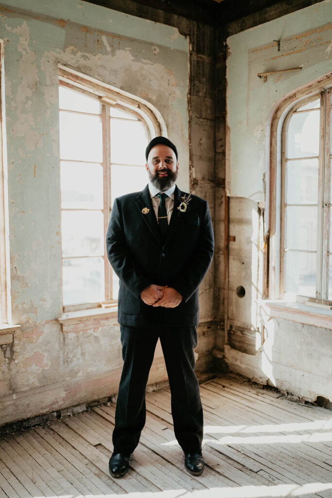 Groom wearing black suit at dark, moody fall wedding