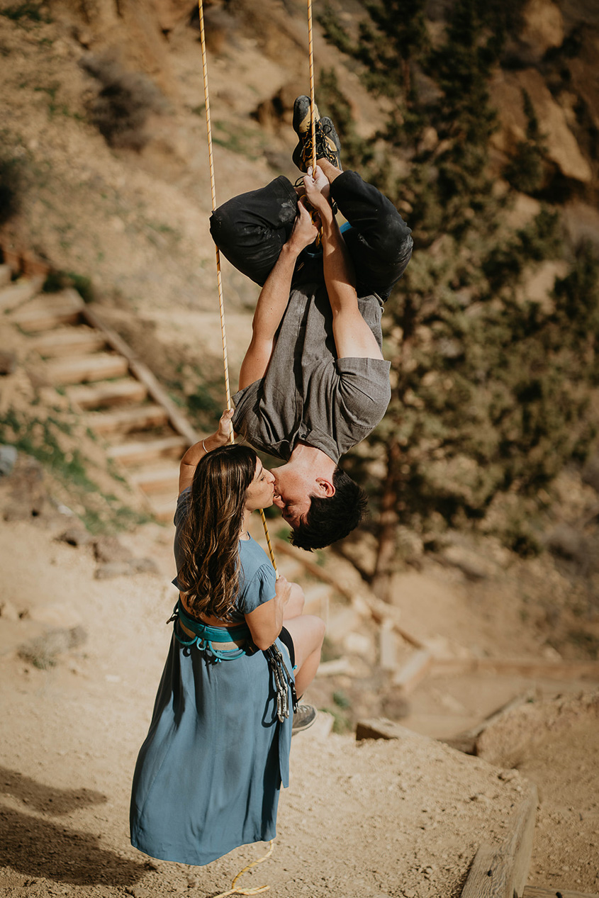 a couple rock climbing kissing each other during their engagement photo session.