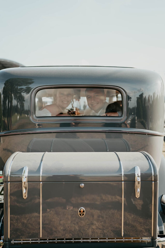 Bride and groom riding in a vintage car