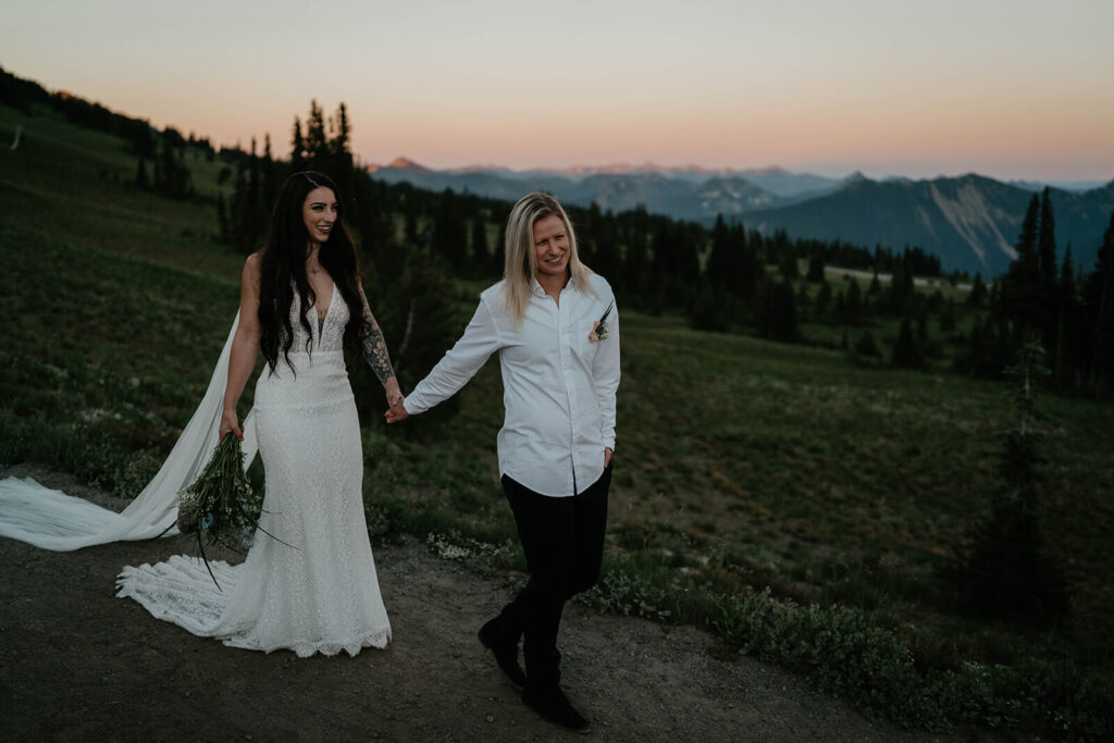 Brides hold hands while walking down a trail at Sunrise, Mt Rainier