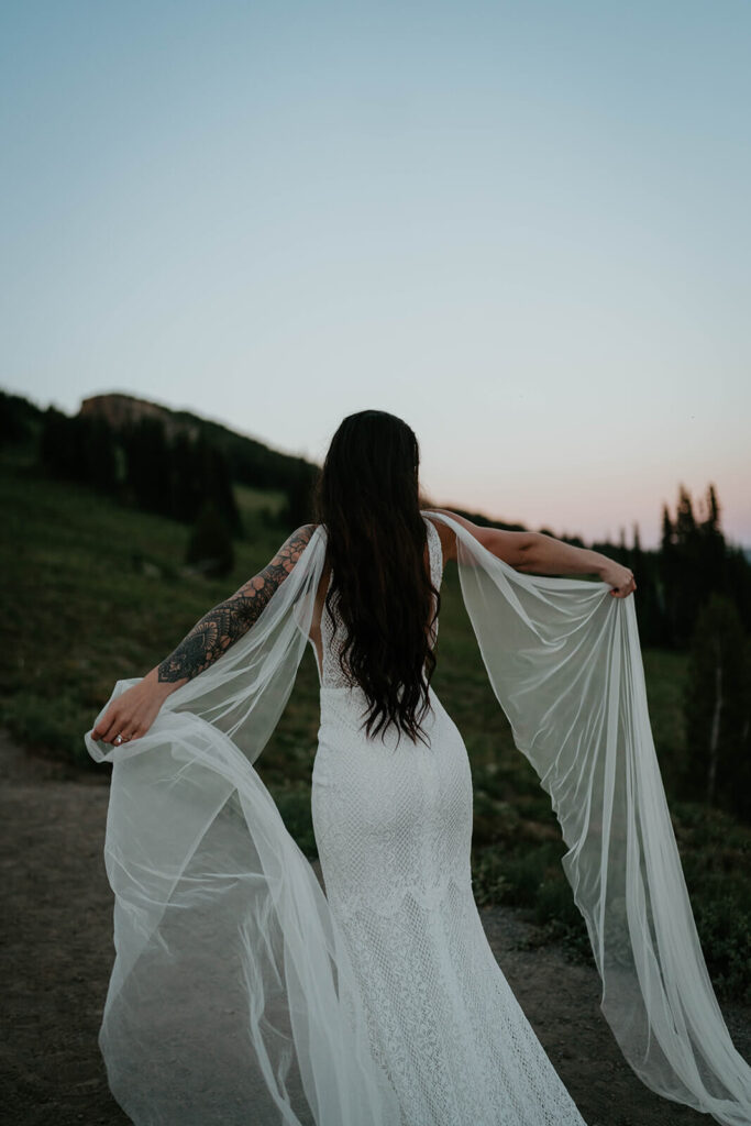 Bride wearing white lace wedding dress with tulle cape sleeves