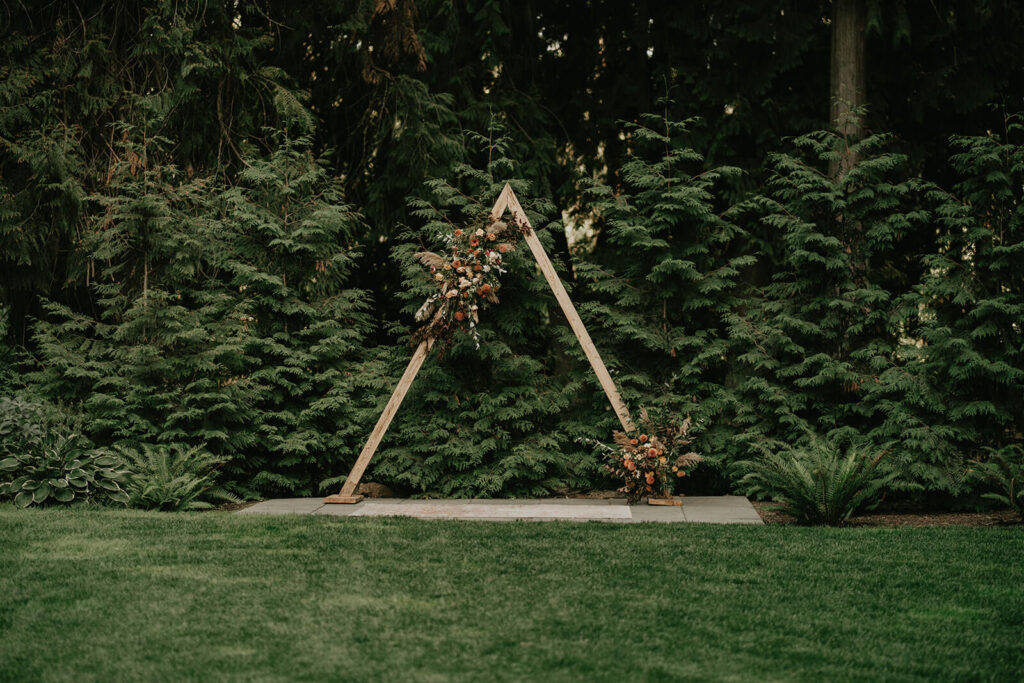 A frame wedding arch with orange, white and green flower arrangements