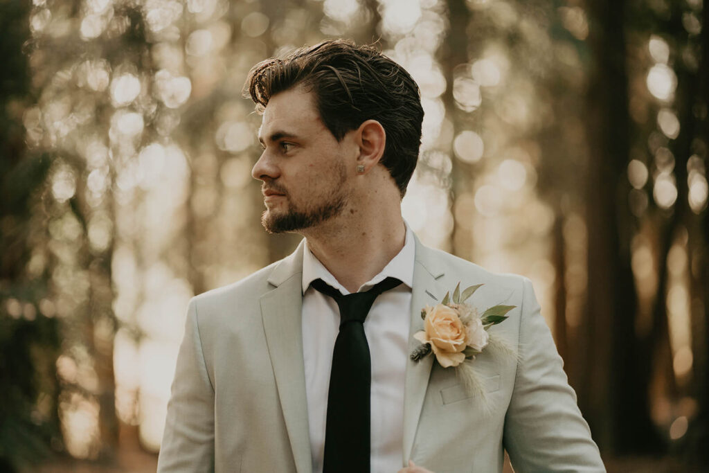 Groom wearing beige linen suit and black tie