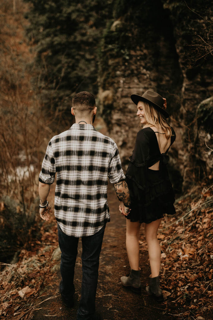 Couple holding hands, walking down the trail at Latourell Falls winter engagement photo session