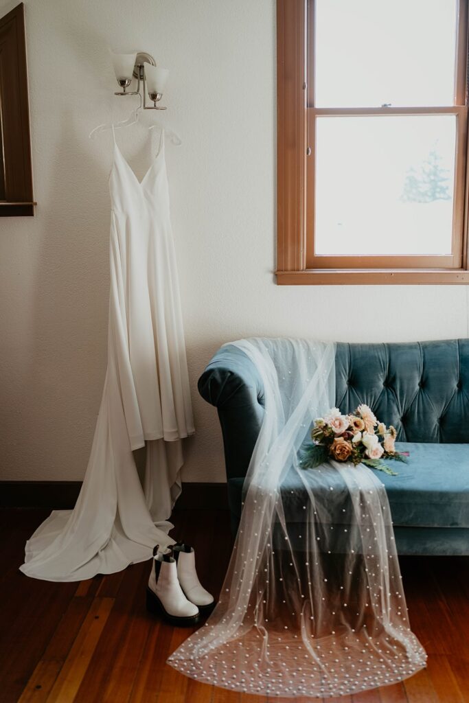 White Brides for a Cause wedding dress with cape sleeves resting on a blue velvet sofa