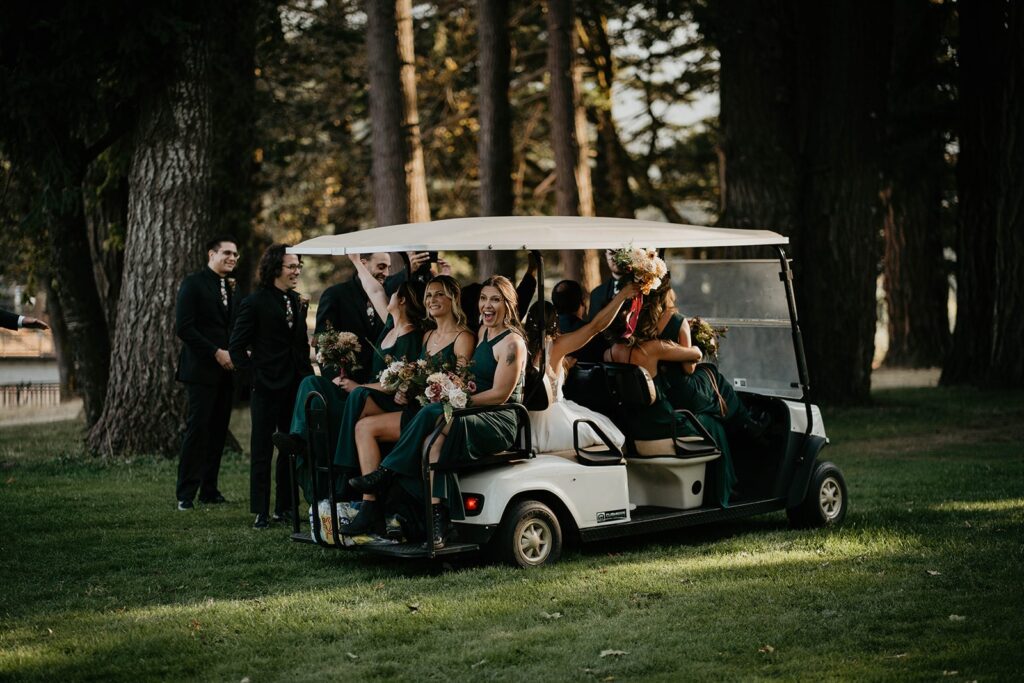 Bridesmaids ride away from the wedding ceremony on a white golf cart