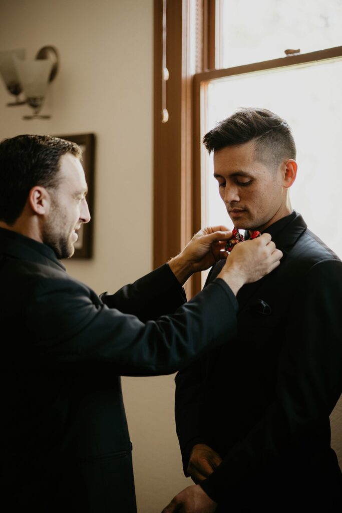 Groomsman helping groom with his bowtie before Thunder Island wedding