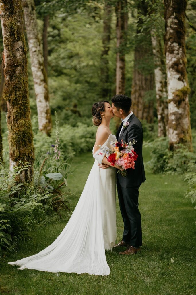 Bride and groom kiss during their wedding portraits on the garden trail at Bridal Veil Lakes