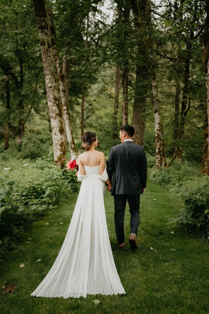 Bride and groom hold hands while walking the garden trail at Bridal Veil Lakes